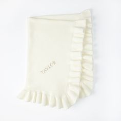 a white blanket with the word taylor written on it and ruffled edges in gold foil