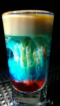 a shot glass filled with colored liquid on top of a table