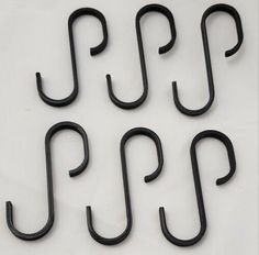 four black hooks are shown on a white surface