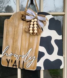 a wooden sign hanging from the side of a window next to a cow print wall