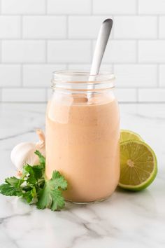 a smoothie in a mason jar with a spoon next to it on a marble counter