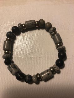 This is a black and gray mix stone bracelet With silver fillers. This looks great on his or her wrist. This item is not as light as a wooden bead around your wrist. But nice around the wrist. Casual Silver Bracelets With Gemstone Beads, Handmade Gray Bracelets For Everyday, Everyday Handmade Gray Bracelets, Casual Gray Bracelets For Everyday, Casual Gray Beaded Bracelets As Gift, Casual Gray Beaded Bracelets, Casual Gray Bracelet, Casual Gray Handmade Bracelet, Casual Handmade Gray Bracelets