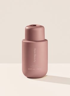 a pink bottle sitting on top of a white table next to a light colored wall