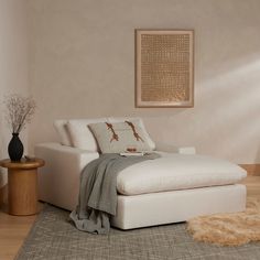 a white couch sitting on top of a wooden floor next to a table and lamp