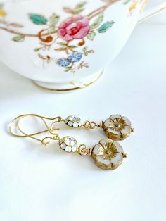 Small delicate white and gold floral earrings inspired by the styles of the Regency Period with a modern twist.  These lightweight flower drops feature small premium Czech glass flowers in white and ivory opal glass with a rustic golden taupe wash highlighting the centers of the blooms.  I added an elegant round 2-layer Austrian crystal and golden brass component made up of tiny crystal clear and white opal vintage stones to really add sparkle.  Romantic floral earrings for your wedding day and Vintage Gold Earrings With Flower Charm, Gold Earrings With Flower Charm In Delicate Style, Elegant Flower Shaped Brass Earrings, Vintage White Flower Drop Earrings, Delicate Gold Brass Flower Earrings, Elegant Adjustable Flower Earrings With Ear Wire, Delicate Flower Charm Earrings, Elegant Brass Flower Earrings, Elegant Brass Flower Earrings Nickel Free