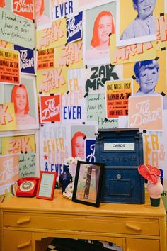 a desk with many pictures on the wall and a radio sitting on top of it