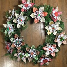 a wreath made out of paper flowers on top of a wooden table