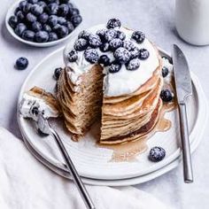 a stack of pancakes topped with blueberries and whipped cream