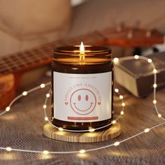 a candle with a smiley face on it sitting next to a string of lights and a guitar