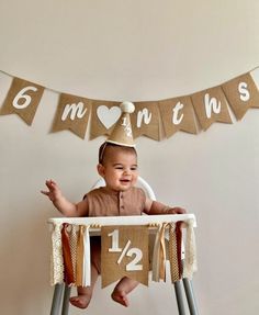 a baby sitting in a high chair wearing a birthday hat and celebrating his first year