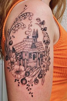 a woman's shoulder with a house and flowers tattoo on her left side arm