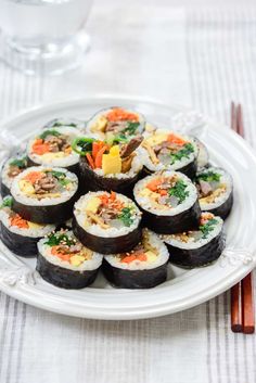 sushi on a white plate with chopsticks next to it