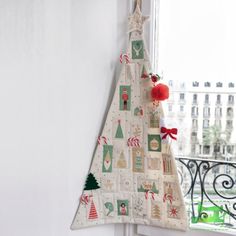 a christmas tree hanging on the side of a window sill in front of a white wall