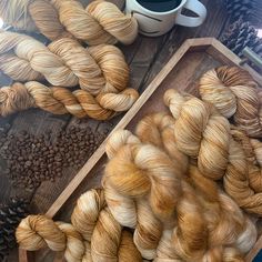 several skeins of yarn sitting next to a cup of coffee on a table