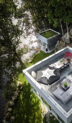 an aerial view of a modern house with outdoor furniture and trees in the back ground