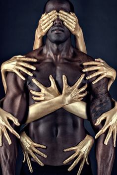 a man with his hands on his face and arms wrapped in gold foil, posing for the camera