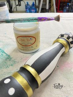 a black and white striped toothbrush sitting on top of a table next to a jar of paint