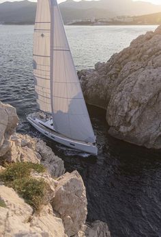 a white sailboat in the water near rocks