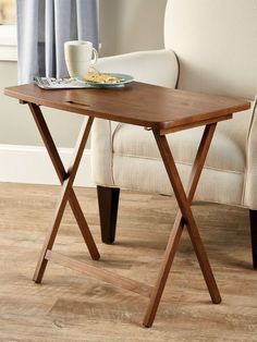 a wooden table with a tray on top of it next to a chair and window