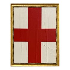 a red and white cross is in a gold frame