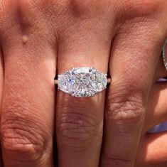 a close up of a person's hand with a diamond ring on their finger