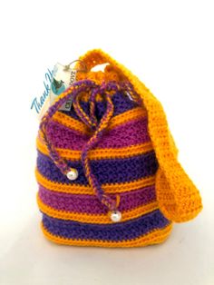 a crocheted bag with a yellow and purple stripe on the front is sitting on a white surface