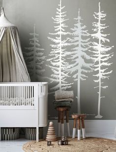 a baby's room with a white crib and trees painted on the wall