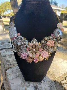 a necklace with flowers and pearls hanging from it's side on a mannequin