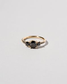 a gold ring with black stones on the side and two diamonds at the top, set in