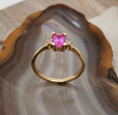 RG496 Pink sapphire-diamond ring. Delicate three stone 14k yellow gold ring mounting set with vivid pink sapphire diamonds. Center stone is .83ct, 6mmx4.2mm, rectangular brilliant cut, intense deep pink - a very sweet stone. Accent stones are 1.7mm round brilliant cut diamonds, SI clarity, G-H color. Would make a beautiful engagement ring. Currently the ring is size 6, will resize at no extra charge, please specify ring size at checkout. Yellow Gold Pink Sapphire Ring With Center Stone, Yellow Gold Ring With Pink Sapphire Center Stone, Gold Pink Sapphire Ring With Accent Stones, Gold Sapphire Ring With Pink Sapphire Accent Stones, Gold Sapphire Ring With Accent Stones, Gold Pink Sapphire Ring With Brilliant Cut, Yellow Gold Pink Sapphire Diamond Ring With Accent Stones, Pink Sapphire Birthstone Ring In Fine Jewelry Style, Yellow Gold Pink Sapphire Ring With Round Cut