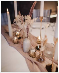 a table topped with candles and vases filled with flowers