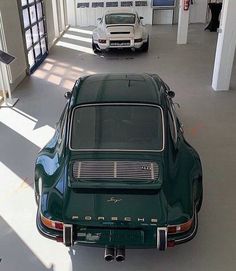 two cars are parked in a garage with the sun shining on them and people walking by