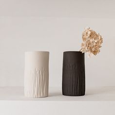 two black and white vases with flowers in them