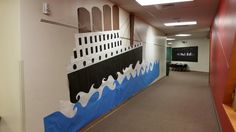 an office hallway with a painted mural of a ship on the wall and tables in the background