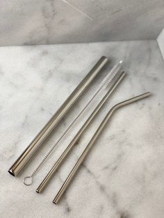 three stainless steel drinking straws on a marble surface