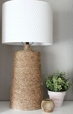 a white lamp sitting on top of a table next to a potted green plant