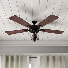 a ceiling fan in a living room with white walls and wood paneling on the ceiling