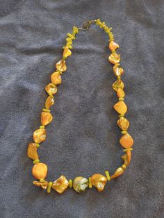 This necklace features golden colored Abalone shell beads and seafoam color dyed coral beads. This is a great addition to anyone who enjoys the beach life. Adjustable Gold Beaded Shell Necklace, Handmade Yellow Pearl Necklace For Gift, Adjustable Multicolor Pearl Necklace For Beach, Adjustable Pearl Necklace For Summer Beach, Gold Single Strand Beaded Necklace For Beach, Bohemian Single Strand Pearl Necklace For Beach, Summer Gold Pearl Necklace For Beach, Yellow Bohemian Jewelry For Vacation, Gold Pearl Necklace For Summer Beach