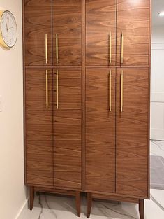 a tall wooden cabinet sitting next to a clock on top of a white countertop