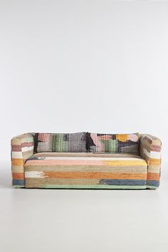 a multicolored striped couch sitting on top of a white floor next to a wall