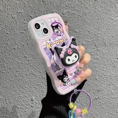 a person holding up a cell phone case with an animal keychain attached to it