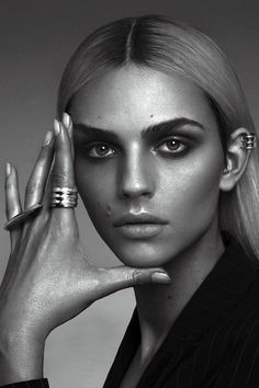 a black and white photo of a woman with rings on her fingers