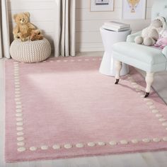 a child's room with a pink rug and teddy bear on the chair in front