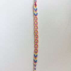 a pink, blue and yellow braided cord on a white surface