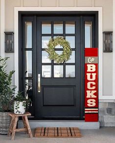 a black front door with a love sign and wreath