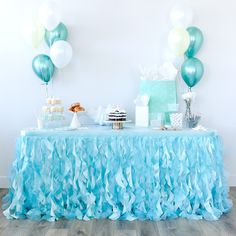 a table topped with cake and balloons on top of a hard wood floored floor