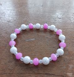 A pink and white beaded bracelet with faux pearls, fit for any occasion. Pink Beaded Pearl Bracelet With Round Beads, Pink Pearl Bracelet With Colorful Beads, Pink Beaded Pearl Bracelet, Handmade Pink Pearl Bracelet, Pink Adjustable Pearl Stretch Bracelet, Adjustable Pink Pearl Stretch Bracelet, Pink Pearl Beaded Bracelets With Colorful Beads, White Beaded Pearl Stretch Bracelet, White Pearl Beaded Stretch Bracelet