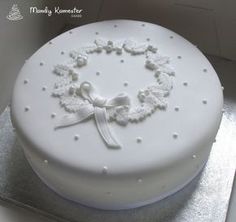 a white cake decorated with pearls and a ribbon