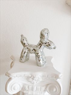 a silver dog statue sitting on top of a white pedestal