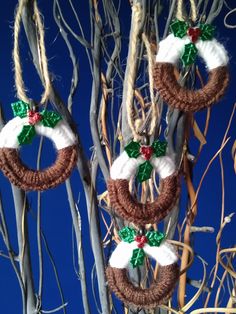 two christmas wreaths hanging from the branches of a tree in front of a blue sky